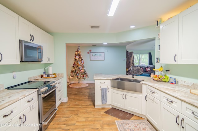 kitchen with light wood finished floors, visible vents, white cabinets, stainless steel appliances, and a sink