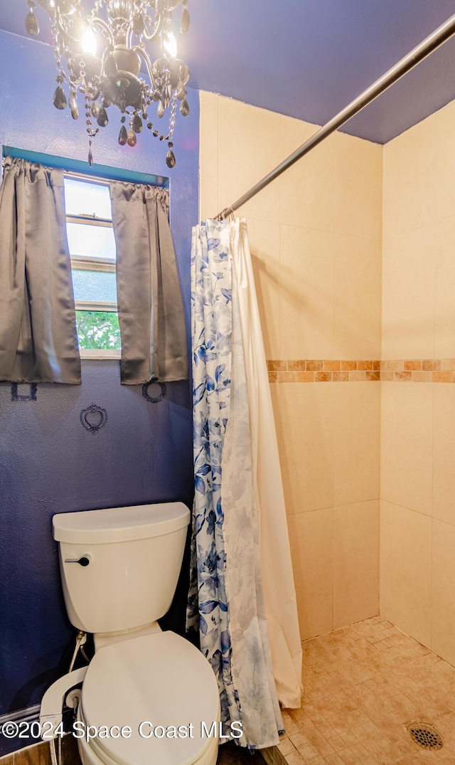 bathroom featuring tiled shower, a notable chandelier, and toilet