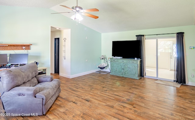 living room featuring ceiling fan, vaulted ceiling, baseboards, and wood finished floors