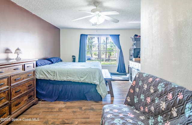 bedroom with a textured ceiling, a ceiling fan, and wood finished floors