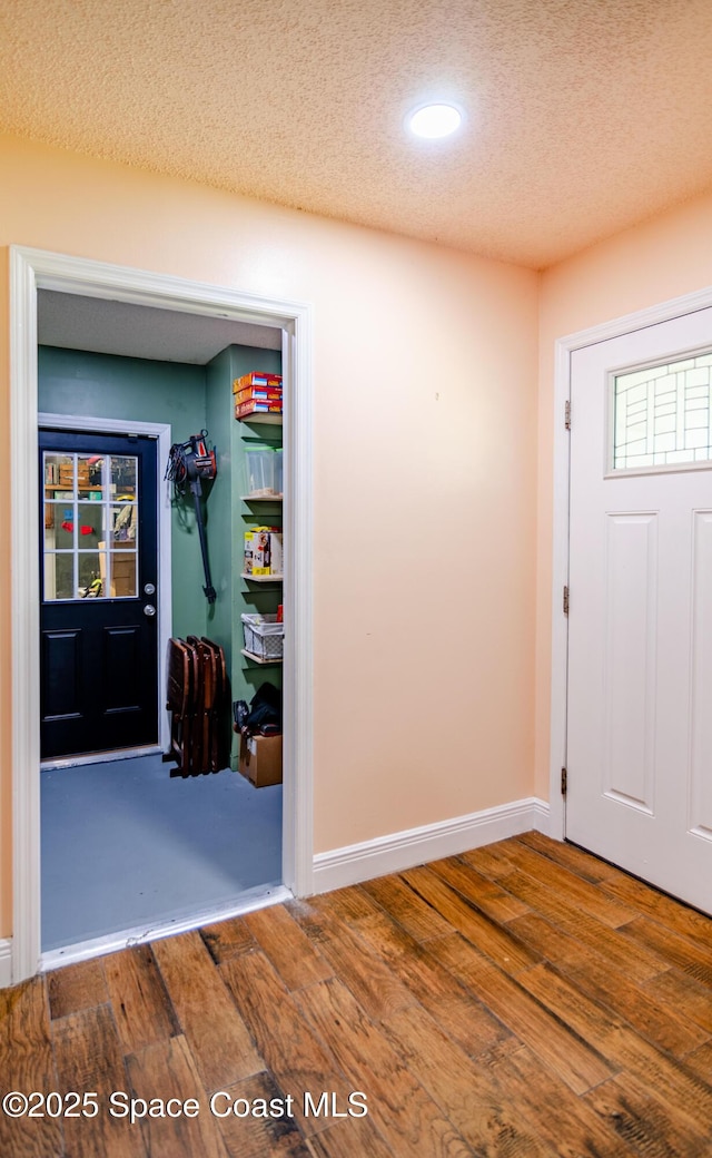 entryway featuring a textured ceiling, wood finished floors, and baseboards