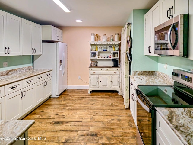 kitchen featuring stainless steel appliances, light wood-type flooring, white cabinets, and light stone counters