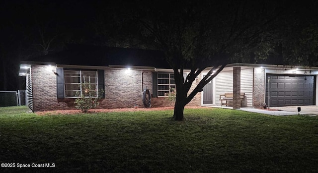 view of front of house with an attached garage, brick siding, fence, concrete driveway, and a lawn