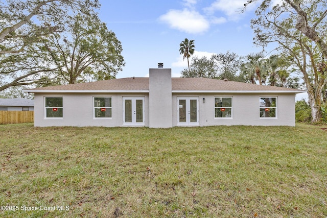 rear view of property featuring french doors and a lawn