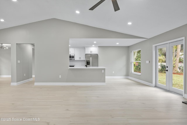 unfurnished living room featuring ceiling fan, french doors, high vaulted ceiling, and light hardwood / wood-style floors