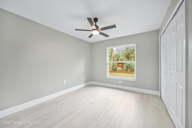 unfurnished bedroom featuring ceiling fan, light hardwood / wood-style floors, and a closet