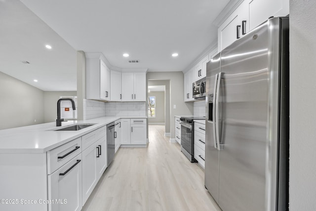 kitchen featuring white cabinetry, sink, stainless steel appliances, light hardwood / wood-style flooring, and decorative backsplash