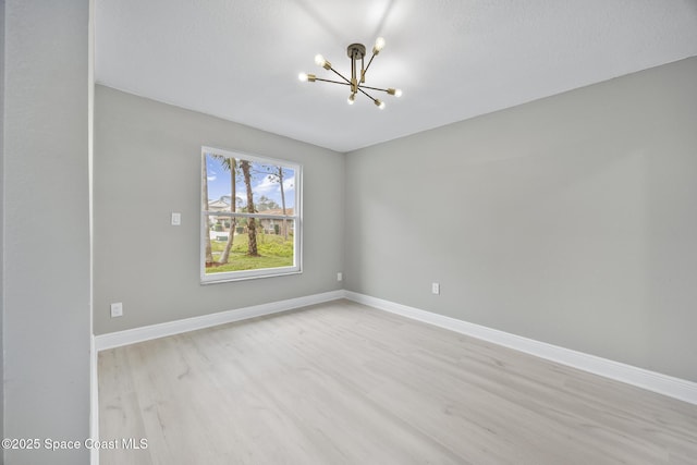 spare room with a chandelier and light hardwood / wood-style flooring