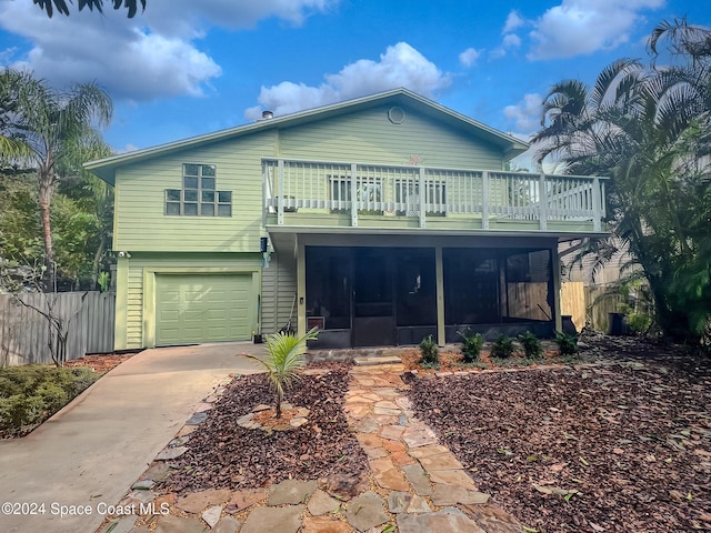 view of front of property with a balcony, a garage, and a sunroom