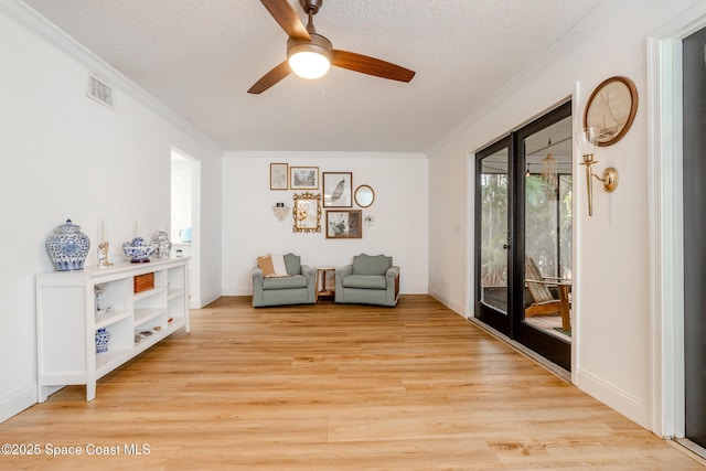 sitting room featuring light hardwood / wood-style flooring, a textured ceiling, and crown molding