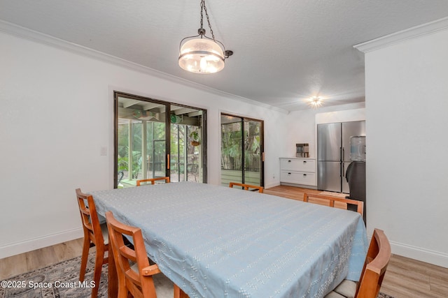 dining area with crown molding, light hardwood / wood-style floors, and a textured ceiling