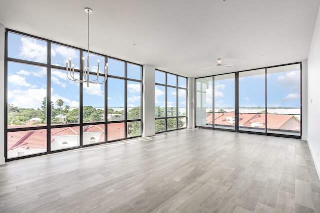 interior space with ceiling fan with notable chandelier, expansive windows, and light hardwood / wood-style flooring