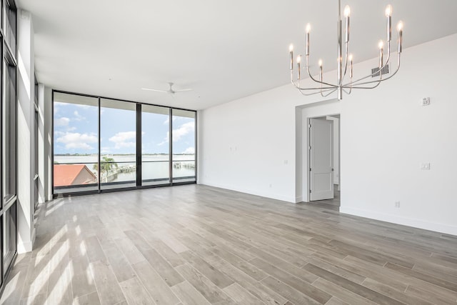 unfurnished room featuring ceiling fan with notable chandelier, hardwood / wood-style flooring, and floor to ceiling windows