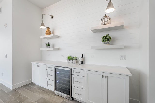 bar with decorative light fixtures, white cabinetry, and wine cooler