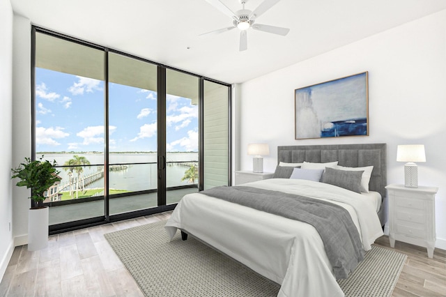 bedroom with access to outside, a water view, light hardwood / wood-style flooring, and ceiling fan