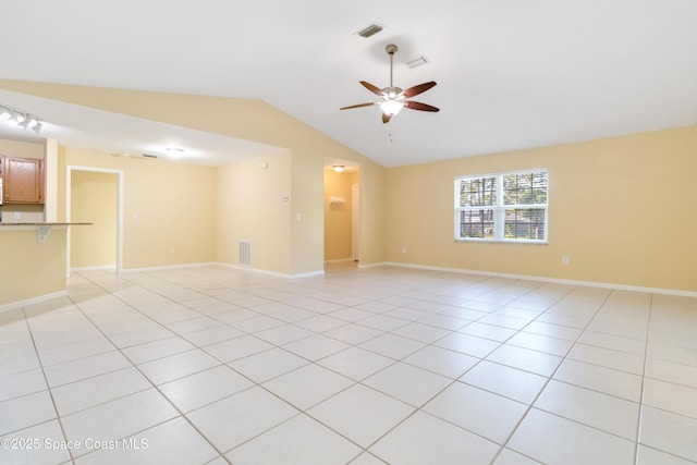 empty room featuring ceiling fan, light tile patterned floors, and vaulted ceiling