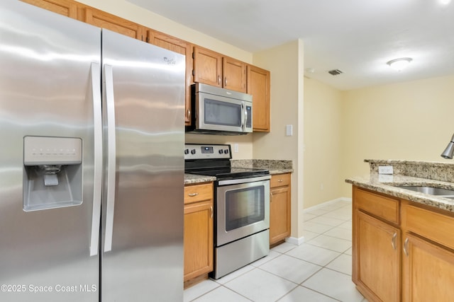 kitchen with light tile patterned flooring, light stone countertops, sink, and appliances with stainless steel finishes