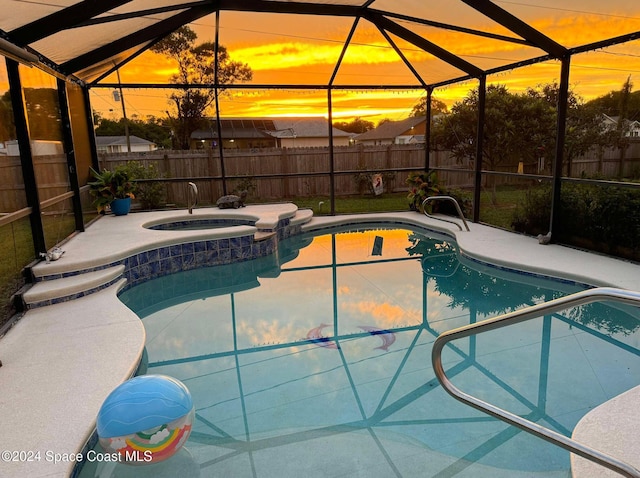 pool at dusk featuring an in ground hot tub and glass enclosure