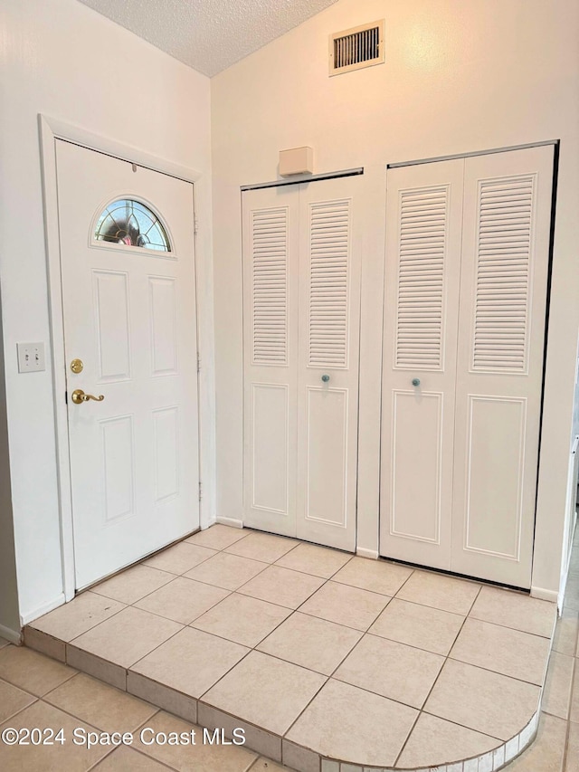 tiled foyer with a textured ceiling