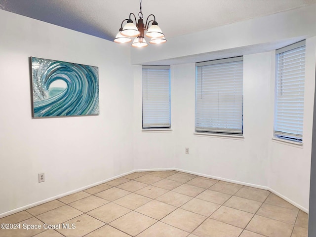 spare room featuring light tile patterned floors, a textured ceiling, and an inviting chandelier