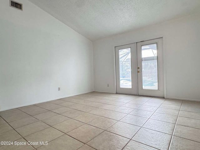 unfurnished room with french doors, a textured ceiling, light tile patterned floors, and lofted ceiling