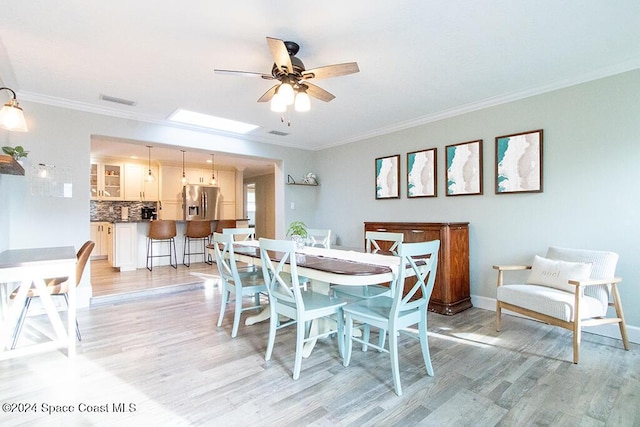 dining area with ceiling fan, light wood-type flooring, and crown molding