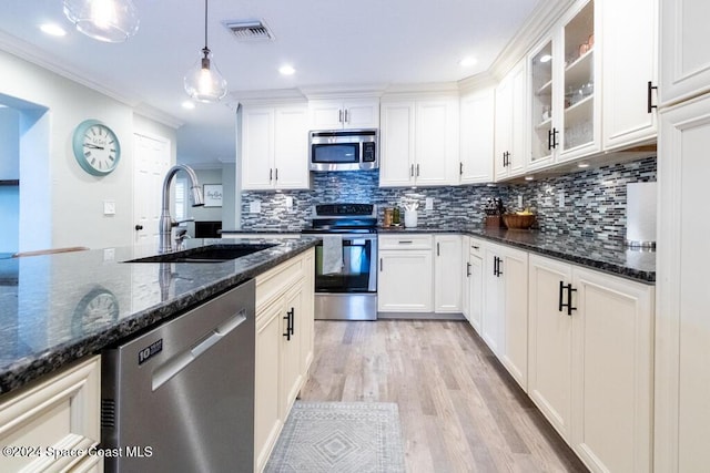 kitchen with white cabinets, hanging light fixtures, sink, appliances with stainless steel finishes, and light hardwood / wood-style floors