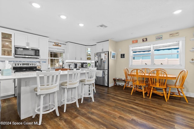 kitchen with white cabinets, a center island, stainless steel appliances, and tasteful backsplash