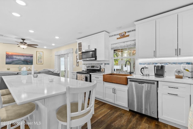 kitchen with decorative backsplash, white cabinetry, sink, and appliances with stainless steel finishes