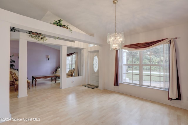 entryway featuring light wood-type flooring, lofted ceiling, and an inviting chandelier