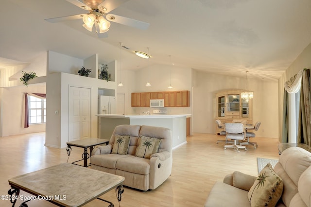 living room featuring high vaulted ceiling, ceiling fan with notable chandelier, and light wood-type flooring