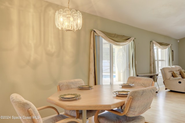 dining space with light hardwood / wood-style floors and an inviting chandelier