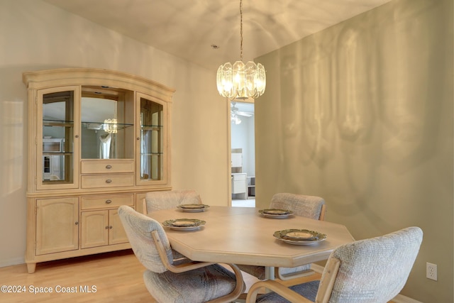 dining space with light hardwood / wood-style flooring and an inviting chandelier