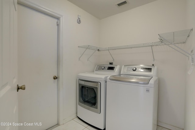 laundry room with washer and dryer and light tile patterned flooring