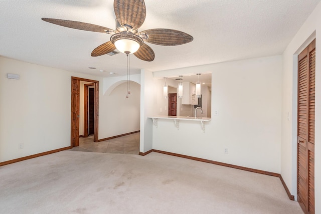 carpeted empty room featuring ceiling fan, sink, and a textured ceiling