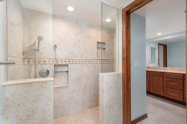 bathroom featuring tile patterned flooring, vanity, and a tile shower