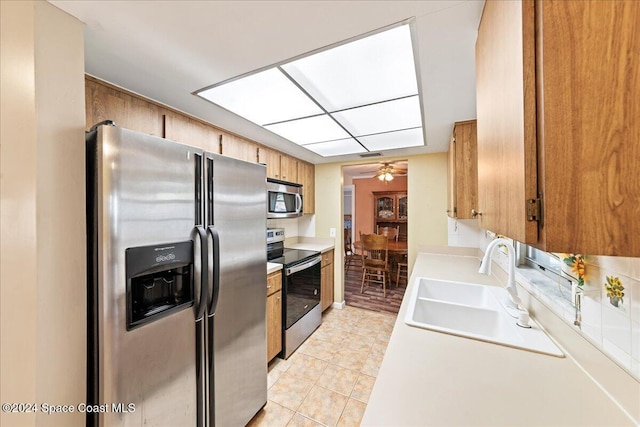 kitchen featuring appliances with stainless steel finishes, light tile patterned floors, ceiling fan, and sink