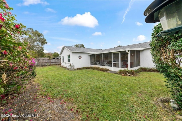 rear view of house with a sunroom and a lawn