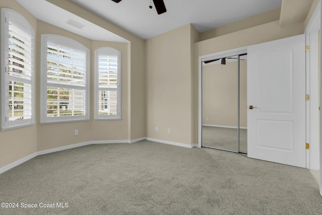 unfurnished bedroom featuring light carpet, a closet, and ceiling fan