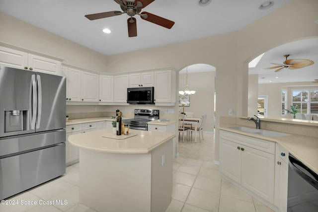 kitchen with sink, light tile patterned floors, stainless steel appliances, white cabinets, and decorative light fixtures