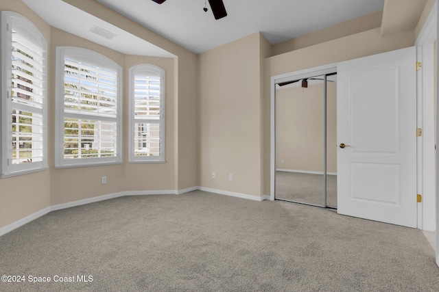 unfurnished bedroom with light colored carpet, ceiling fan, and a closet