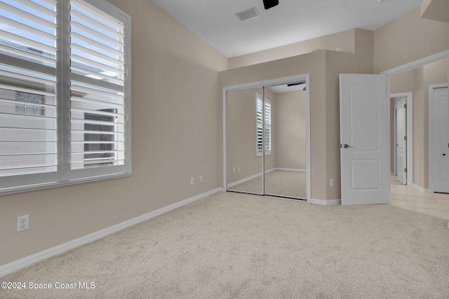 unfurnished bedroom with light colored carpet and a closet