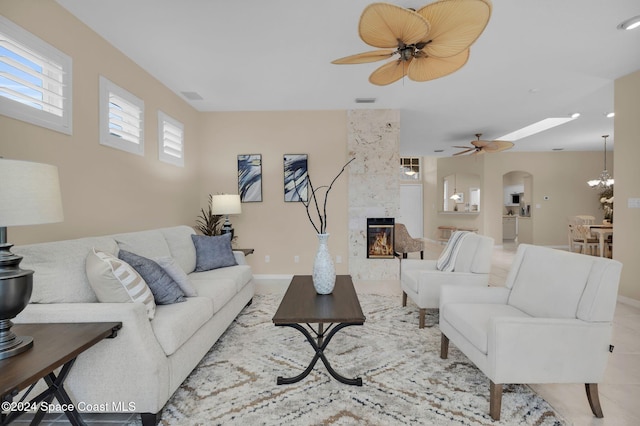 living room featuring ceiling fan with notable chandelier and a high end fireplace