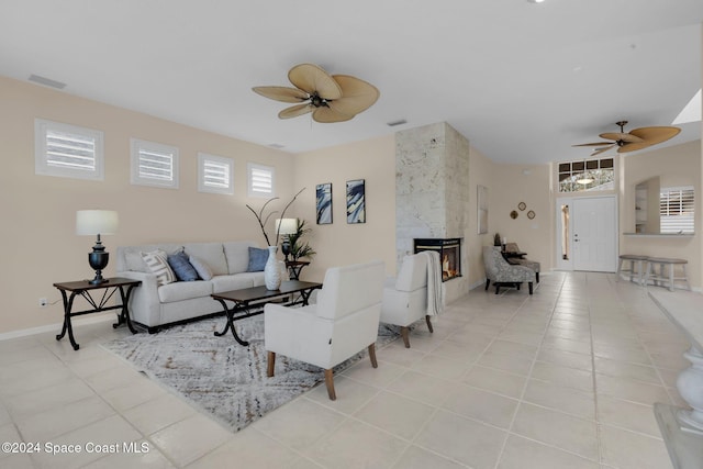 living room with ceiling fan, a premium fireplace, and light tile patterned floors