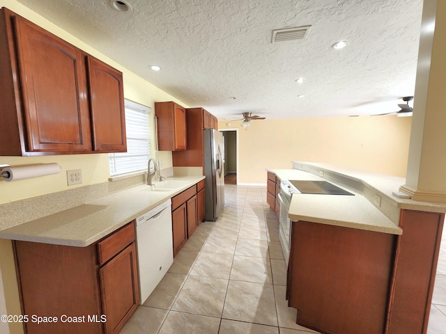 kitchen with ceiling fan, sink, a textured ceiling, white appliances, and light tile patterned floors