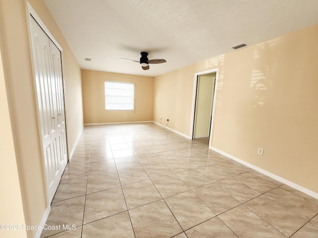 empty room with light tile patterned floors, a textured ceiling, and ceiling fan