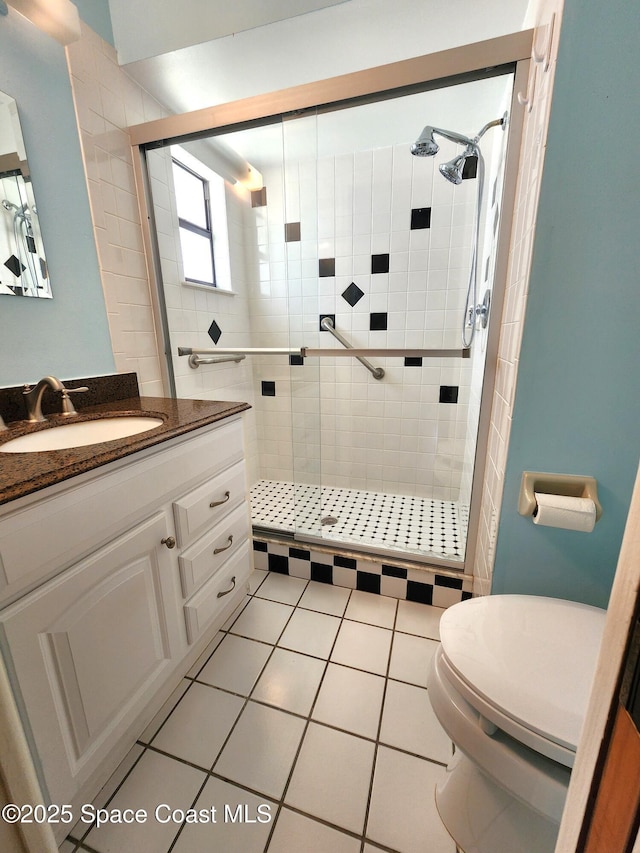 bathroom with tile patterned floors, vanity, toilet, and walk in shower