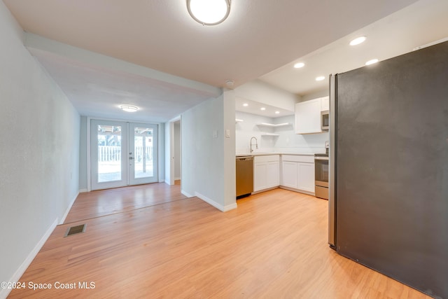 kitchen with white cabinetry, french doors, stainless steel appliances, and light wood-type flooring