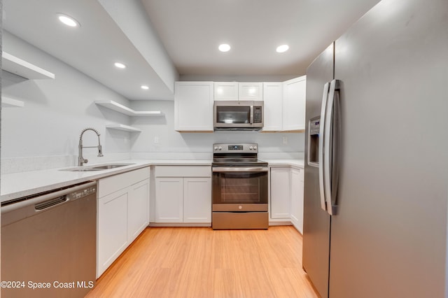 kitchen featuring sink, white cabinetry, stainless steel appliances, and light hardwood / wood-style flooring