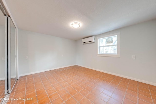 interior space featuring a textured ceiling, a wall unit AC, and light tile patterned flooring